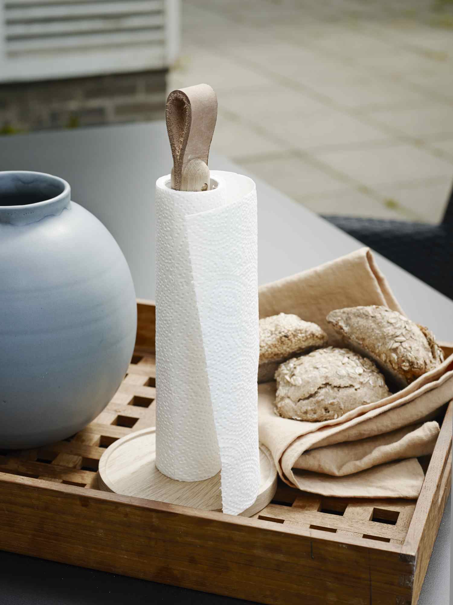 Norr Küchenrollenhalter von Skagerak: Küchenrolle auf Holztablett mit Brötchen und Vase.