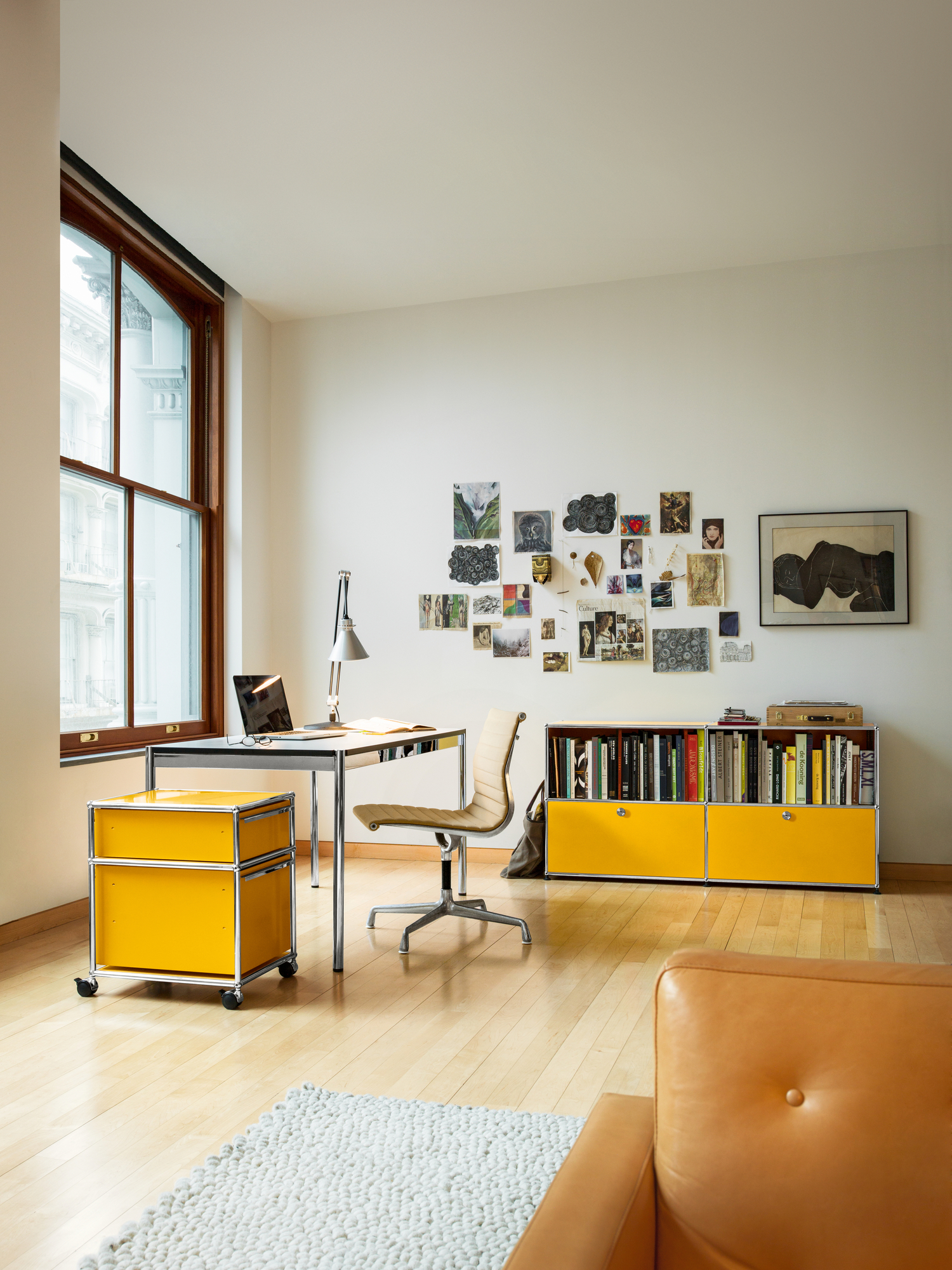 USM Haller Sideboard rubinrot im modernen Wohnzimmer mit Schreibtisch und Bücherregal.