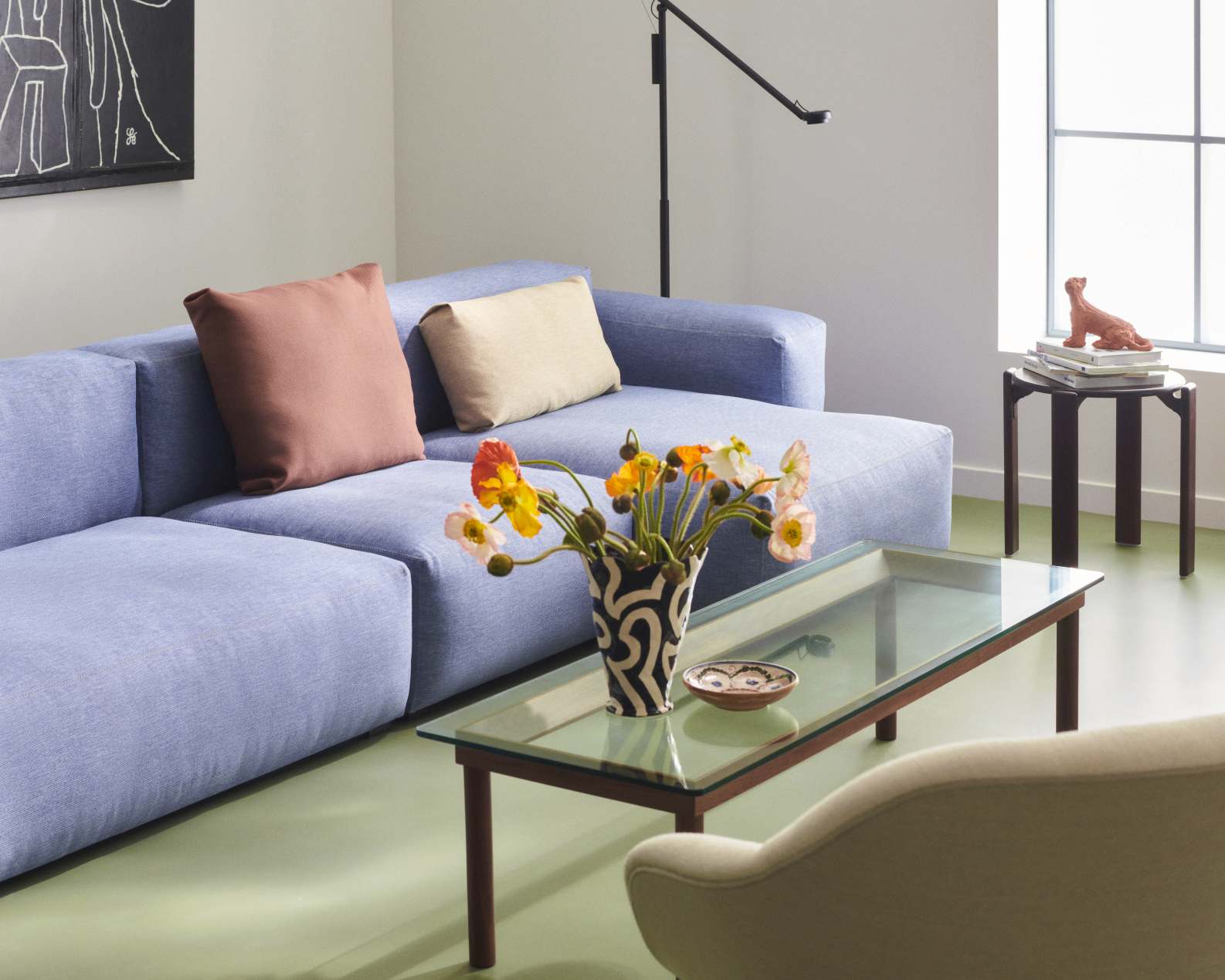 Hellblaues Mags Sofa mit Kissen und Glas-Couchtisch in einem modernen Wohnzimmer.