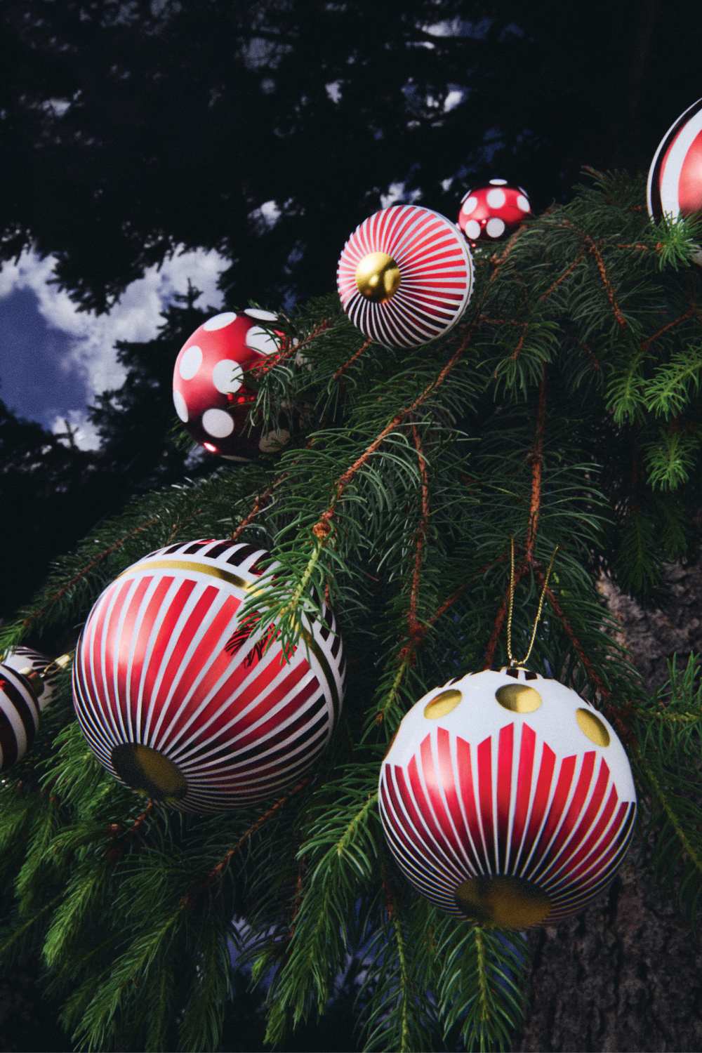 Nahaufnahme von Alessi Weihnachtskugeln NZ04 1 Delight mit roten Streifen und Punkten am Weihnachtsbaum.