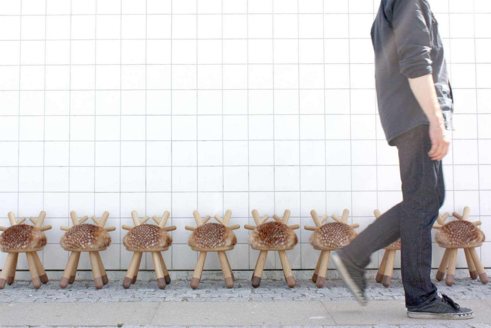 Reihe von Bambi Chair Kinderstühlen von EO  aus Holz mit Fellimitat vor weißer Wand.