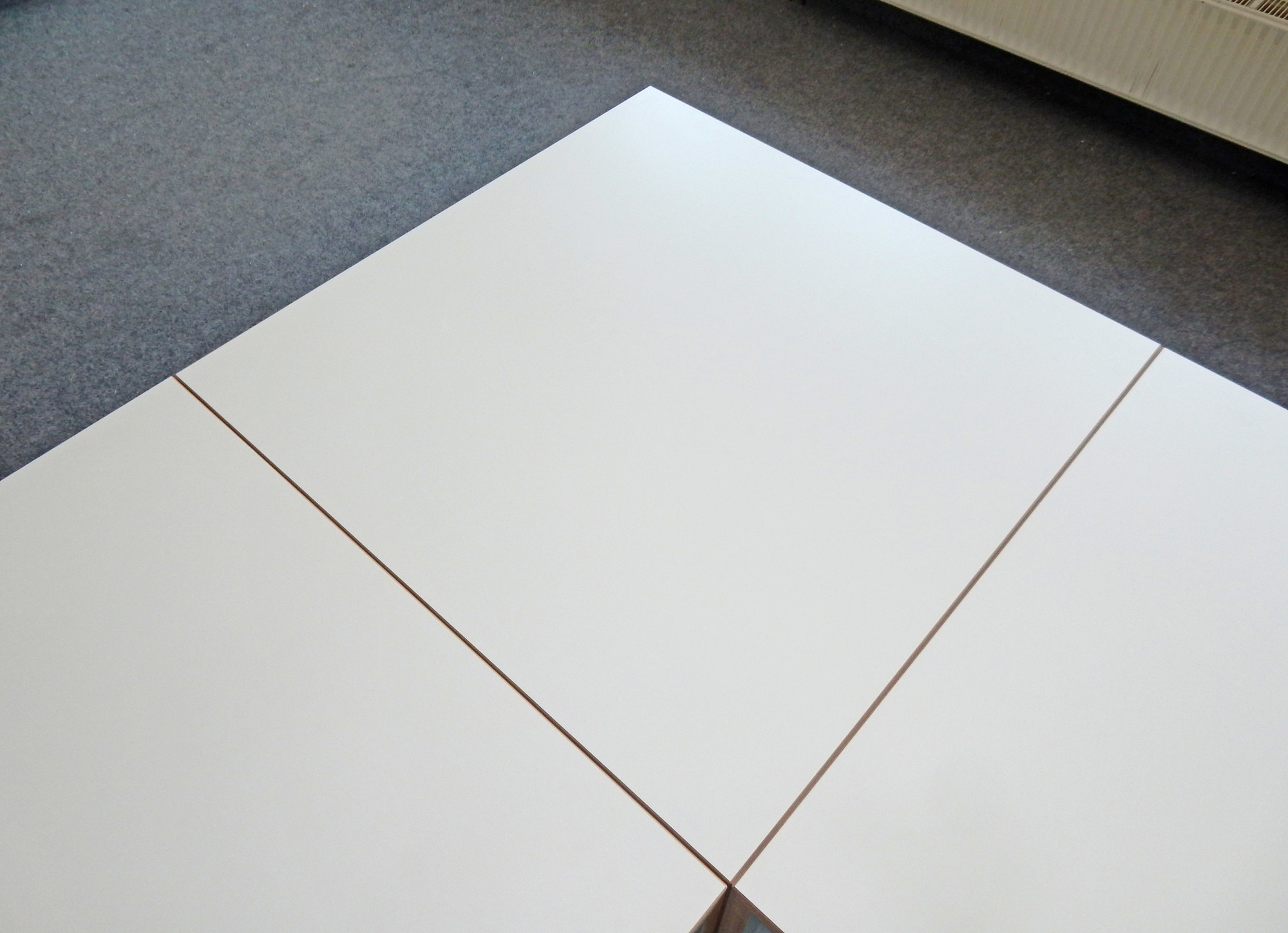 Detailaufnahme der Tischplatte vom Tojo Freistell Tisch, ein großer, weißer Design-Tisch für moderne Wohnräume.