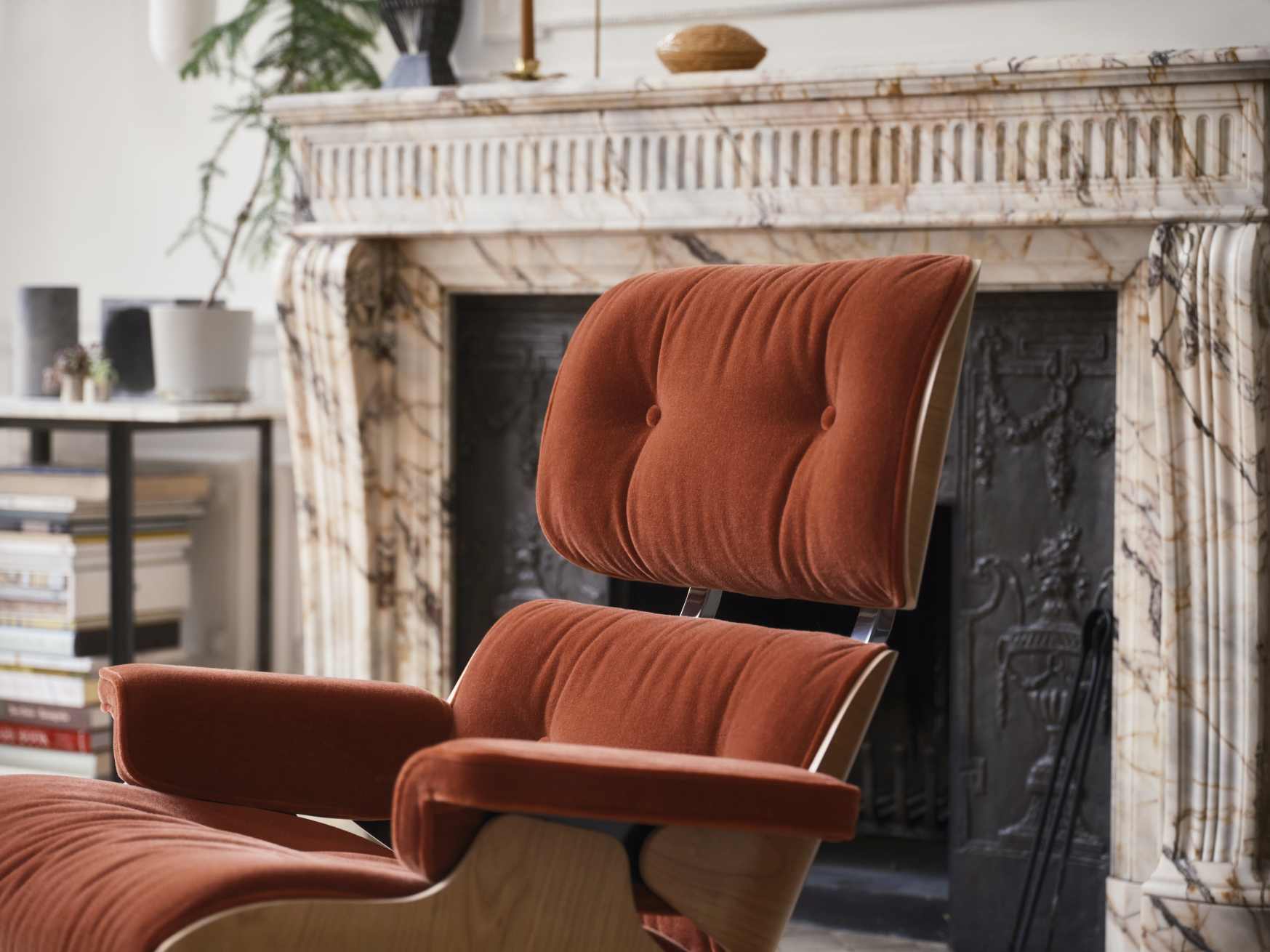 Nahaufnahme eines braunen Eames Lounge Chairs von Vitra vor einem Kamin, Luxusmöbel für Wohnzimmer.