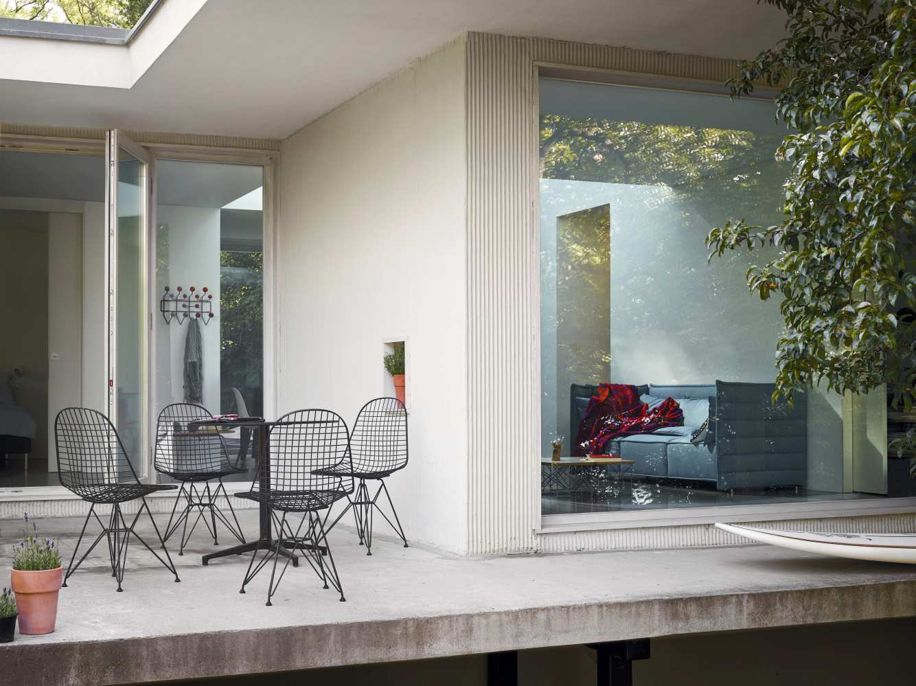 Vitra Bistro Table runder Gartentisch mit vier Drahtstühlen auf einer Terrasse.