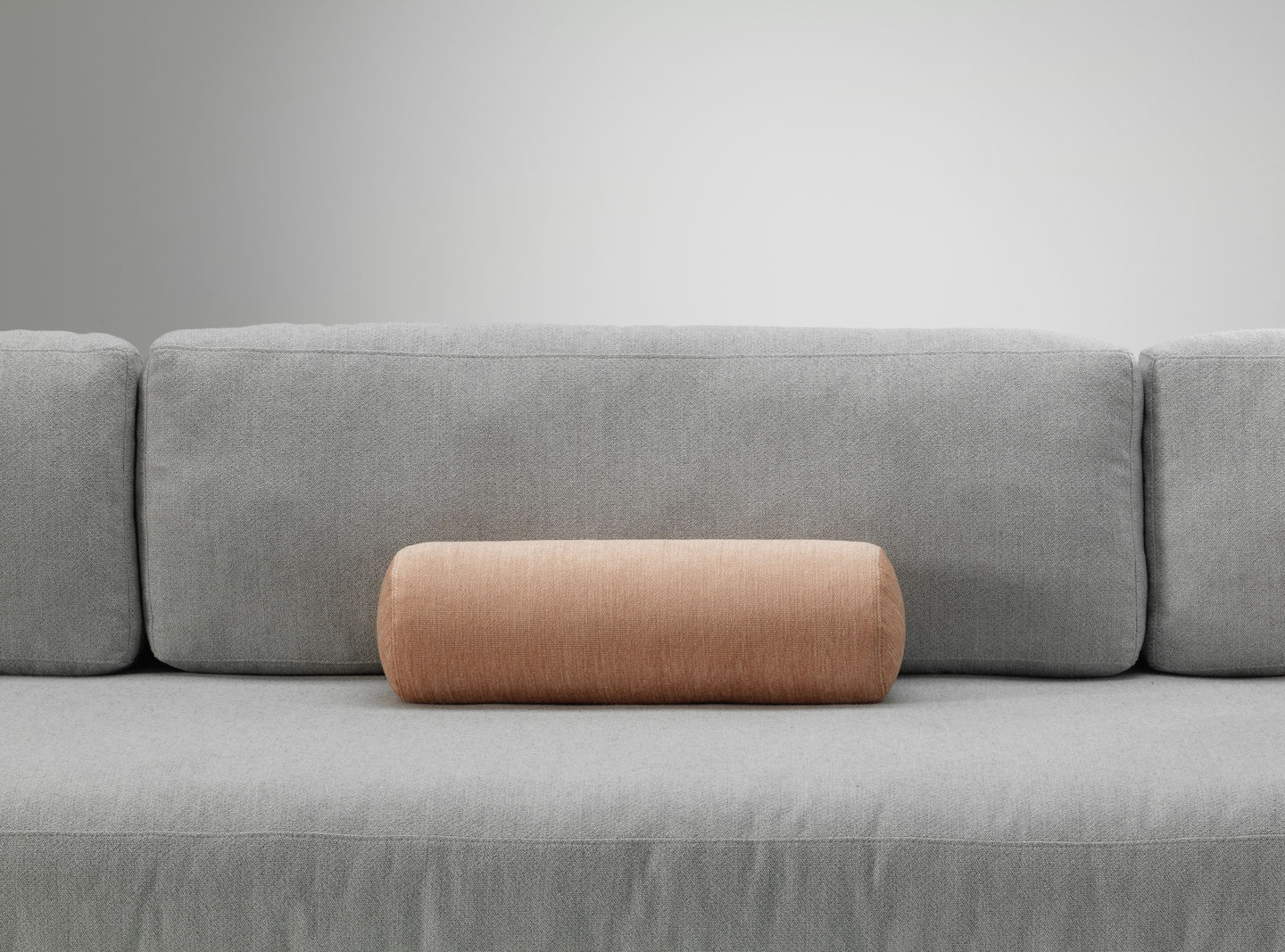 Vitra Kissen: Länglich, orangefarbenes Sofakissen auf einem grauen Sofa, modernes Wohnaccessoire für stilvolles Interieur.