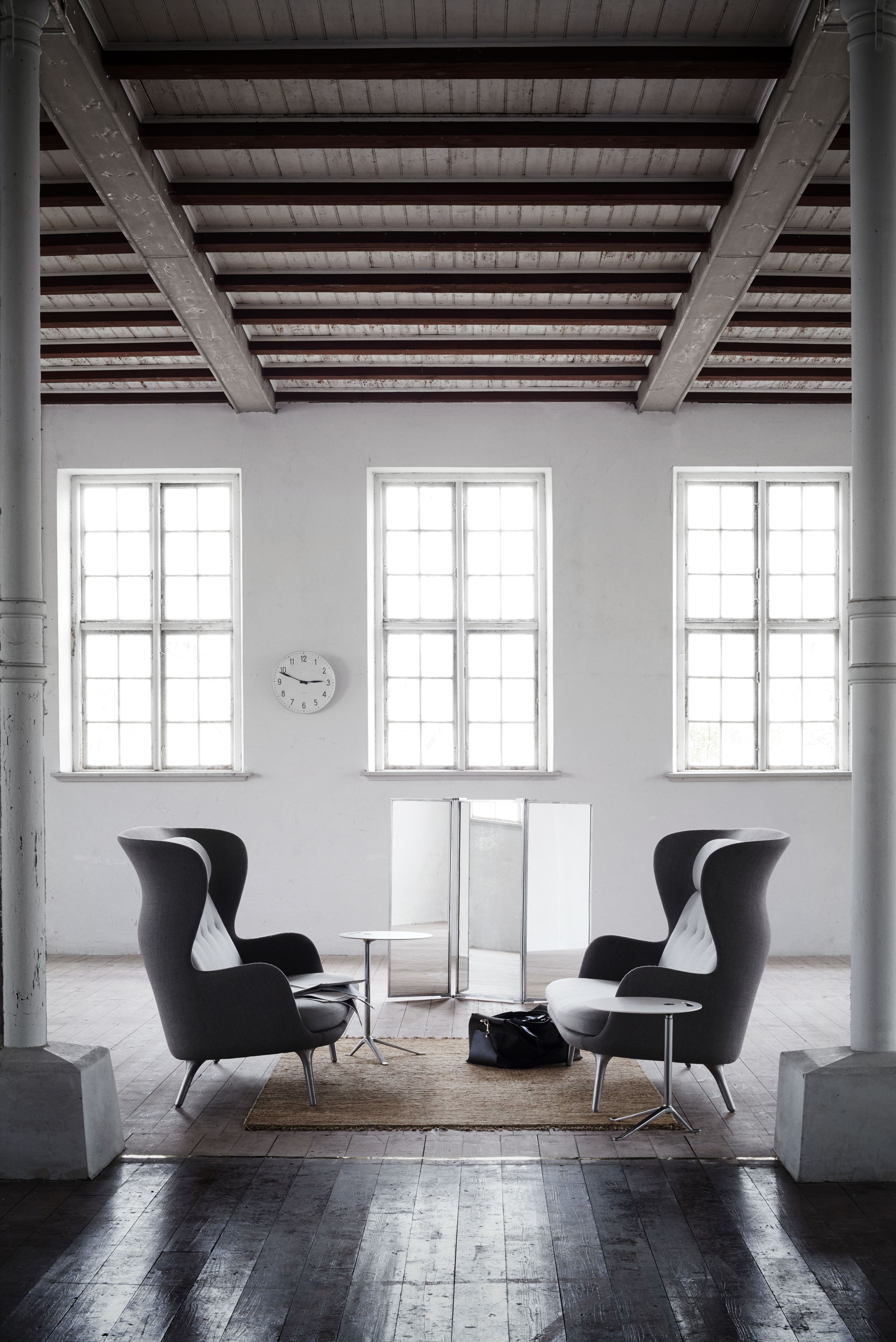 Zwei graue Fritz Hansen Ro Sessel aus Holz mit Beistelltischen in einem hellen Raum.