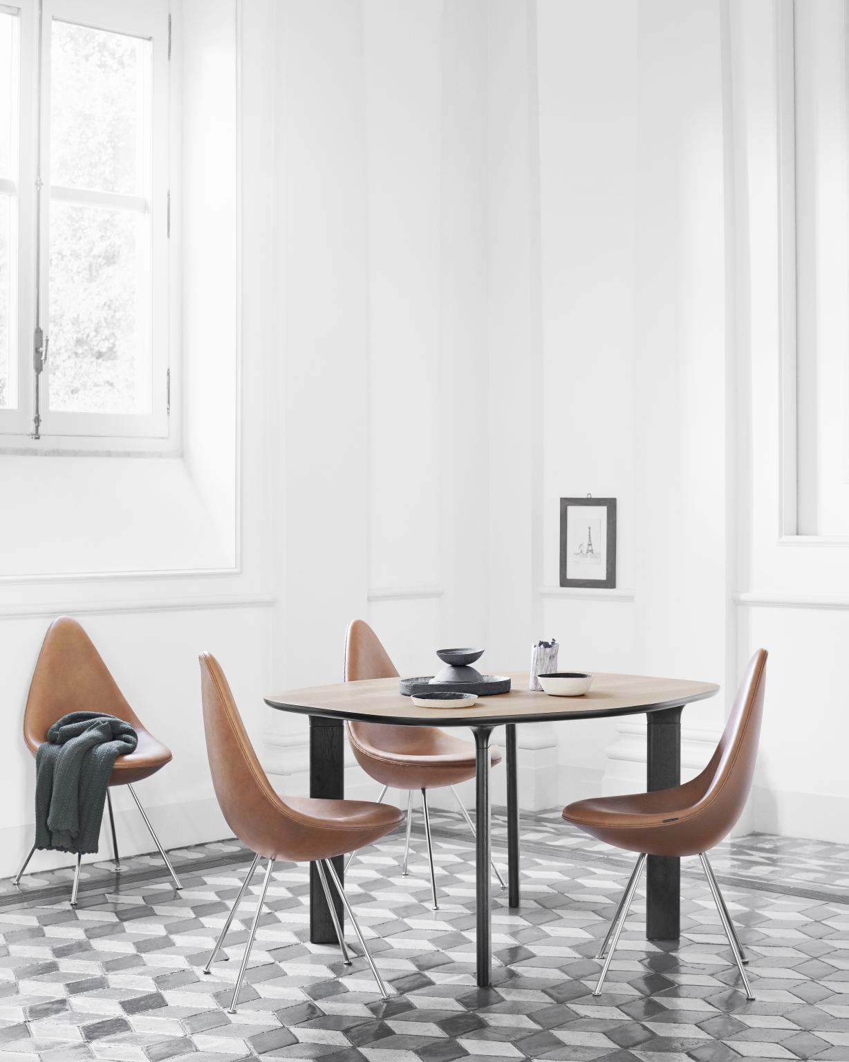 Esszimmer mit rundem Tisch und vier braunen Fritz Hansen Drop Stühlen mit verchromten Beinen.