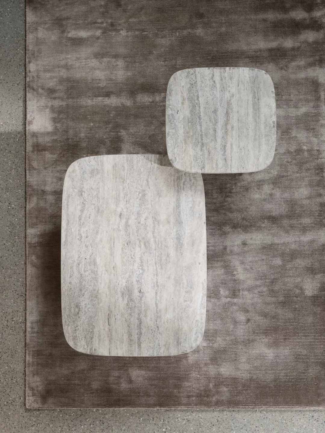 Blomus Volos Couchtisch aus Travertin, zwei quadratische Tische auf einem braunen Teppich, modernes Wohnzimmerdesign.