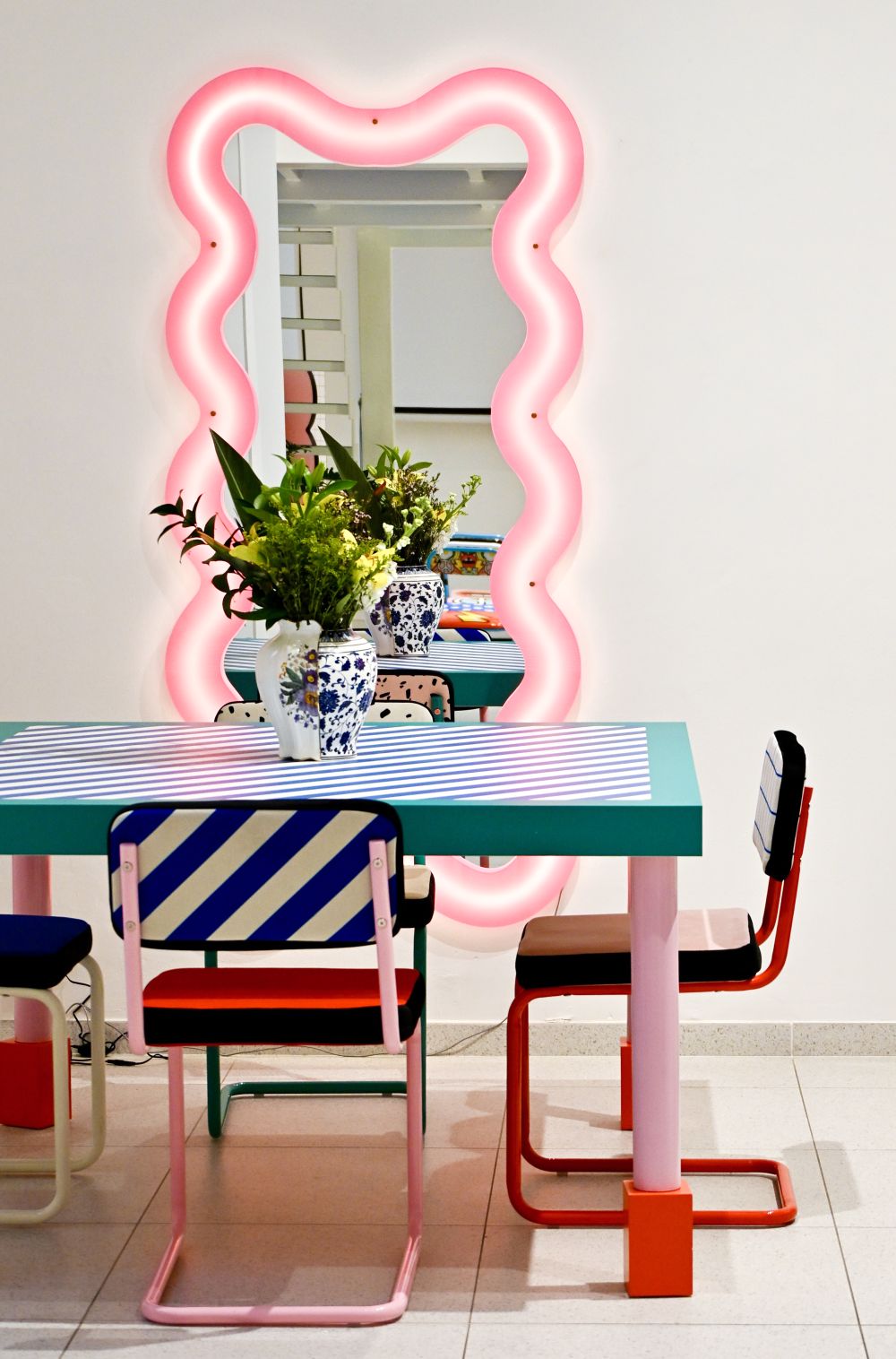 Supersquare Table Esstisch von Seletti mit blau-weiß gestreifter Tischplatte, bunten Stühlen und pinkem Spiegel.