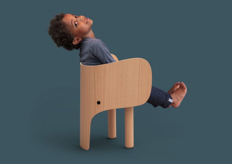 Junge sitzt entspannt auf einem hellen Holz Kinderstuhl, minimalistisches Design für Kinderzimmer.