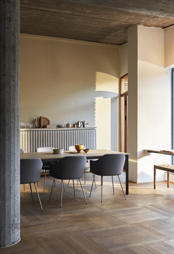 AndTradition Drip Table HW58 Esstisch mit Stühlen in modernem Esszimmer mit Holzboden und Betonpfeiler.