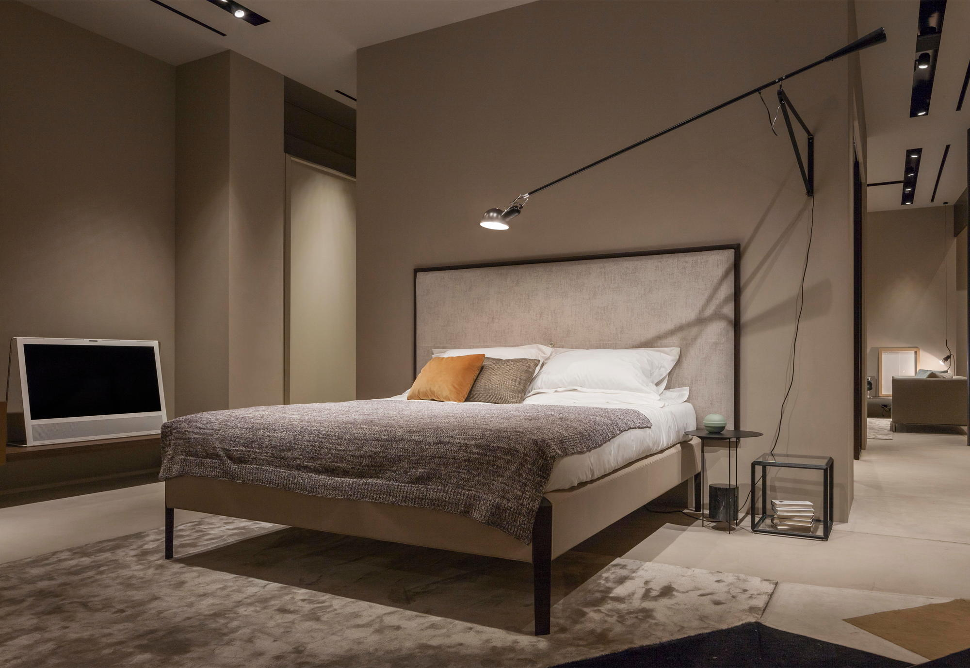 Schlafzimmer mit Bett und schwarzer Flos 265 Wandleuchte für indirekte Beleuchtung über dem Nachttisch.