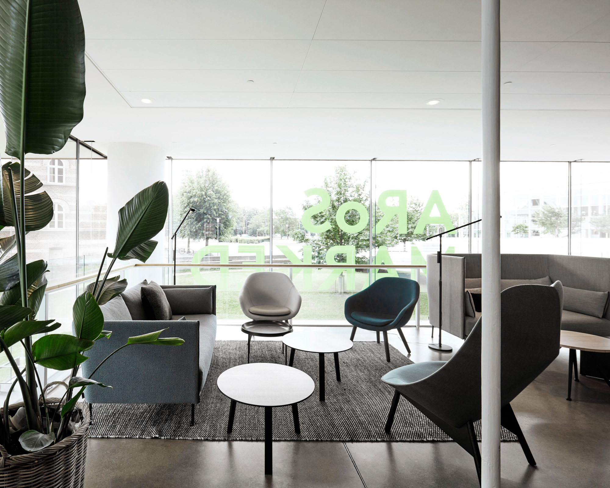 Heller Raum mit Hay About a Lounge AAL 82 Sesseln und Sofas in Grau- und Blautönen.