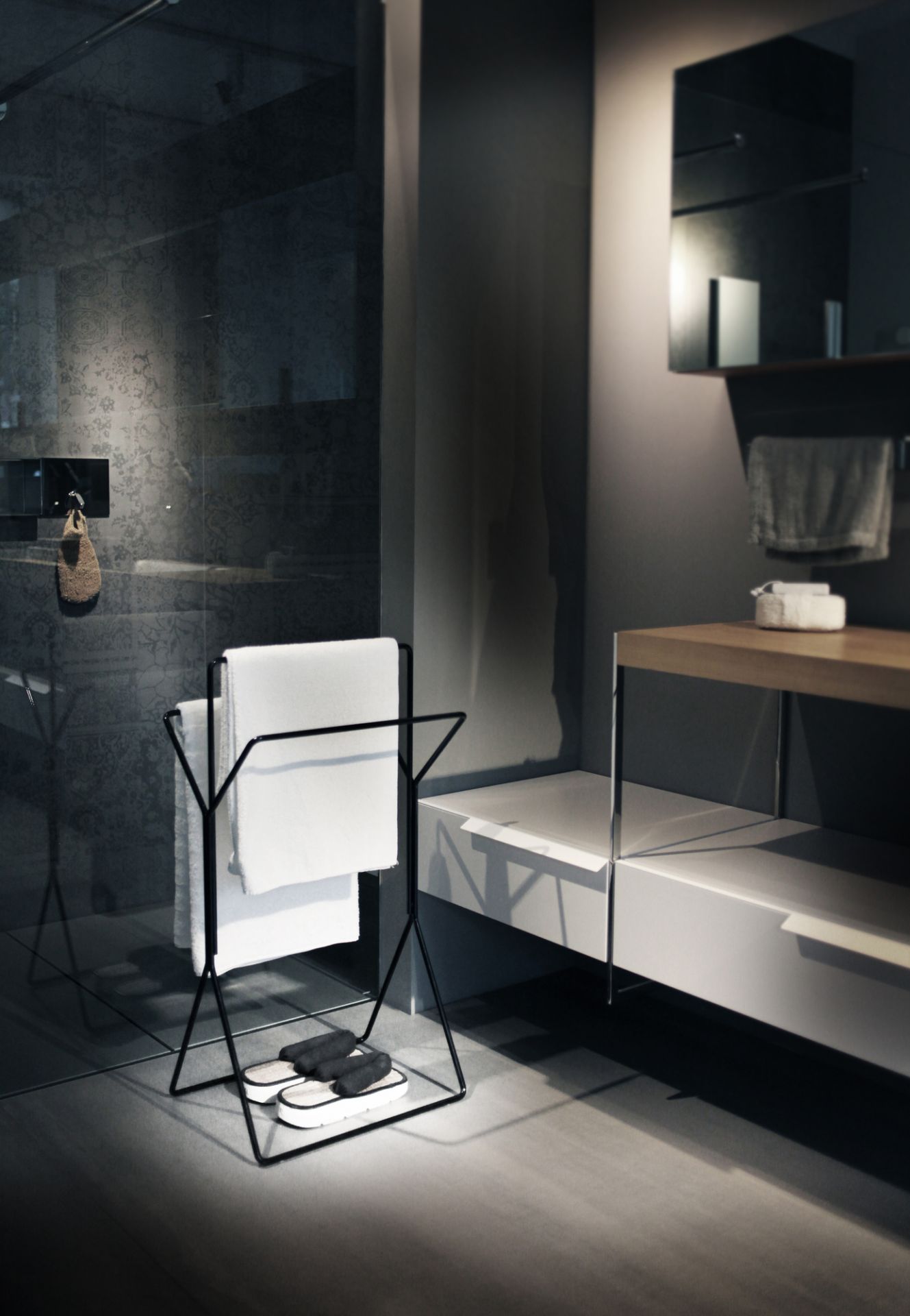 Schwarzer Handtuchständer mit weißen Handtüchern und Badeschuhen im modernen Badezimmer. Badaccessoires für stilvolles Badezimmerdesign.