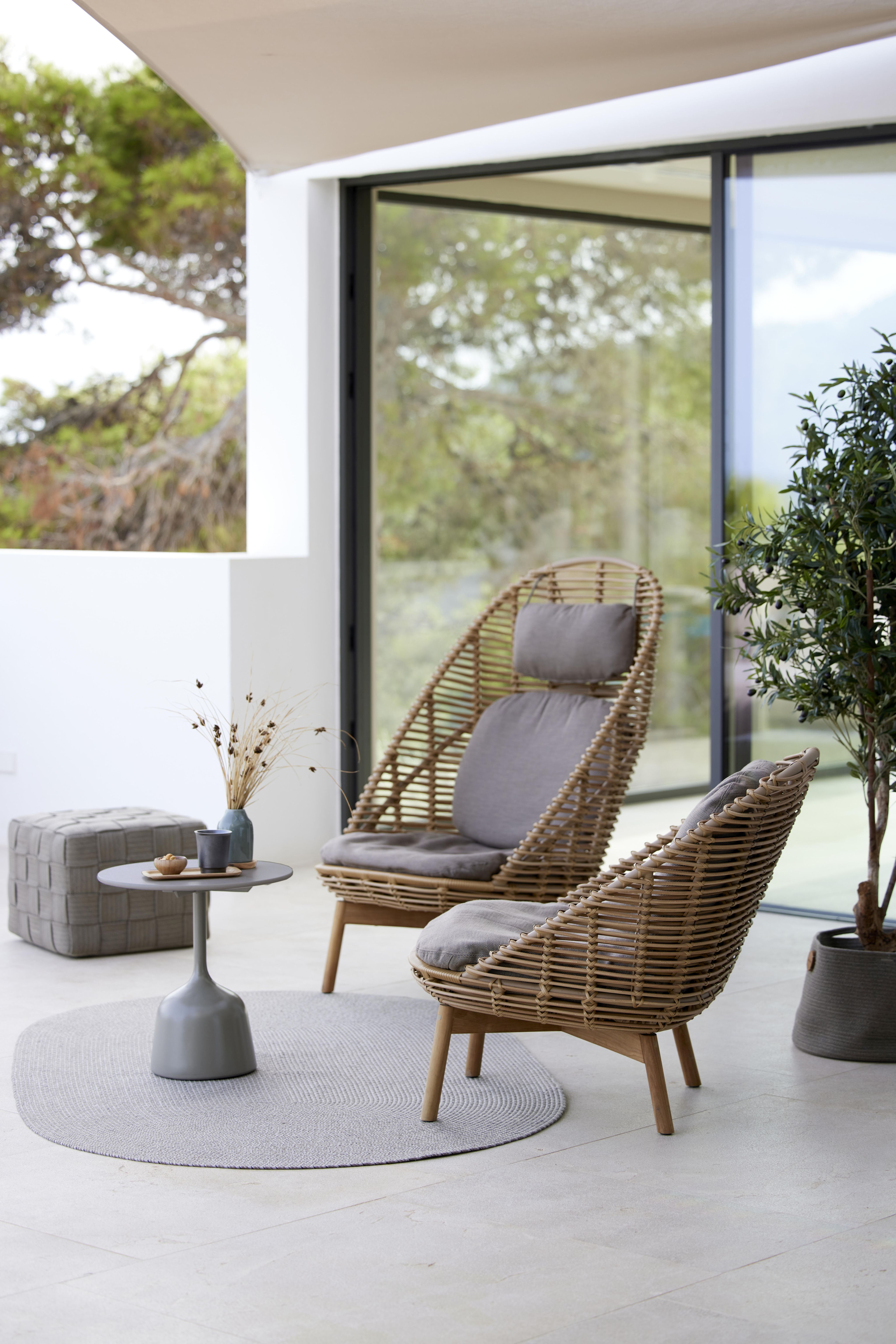 Zwei Cane-Line Highback Sessel aus Rattan mit Teakholzbeinen und grauen Kissen.