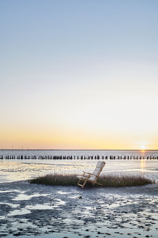 BM5568 Borge Mogensen Liegestuhl mit Kissen von Carl Hansen & Søn am Strand bei Sonnenuntergang.