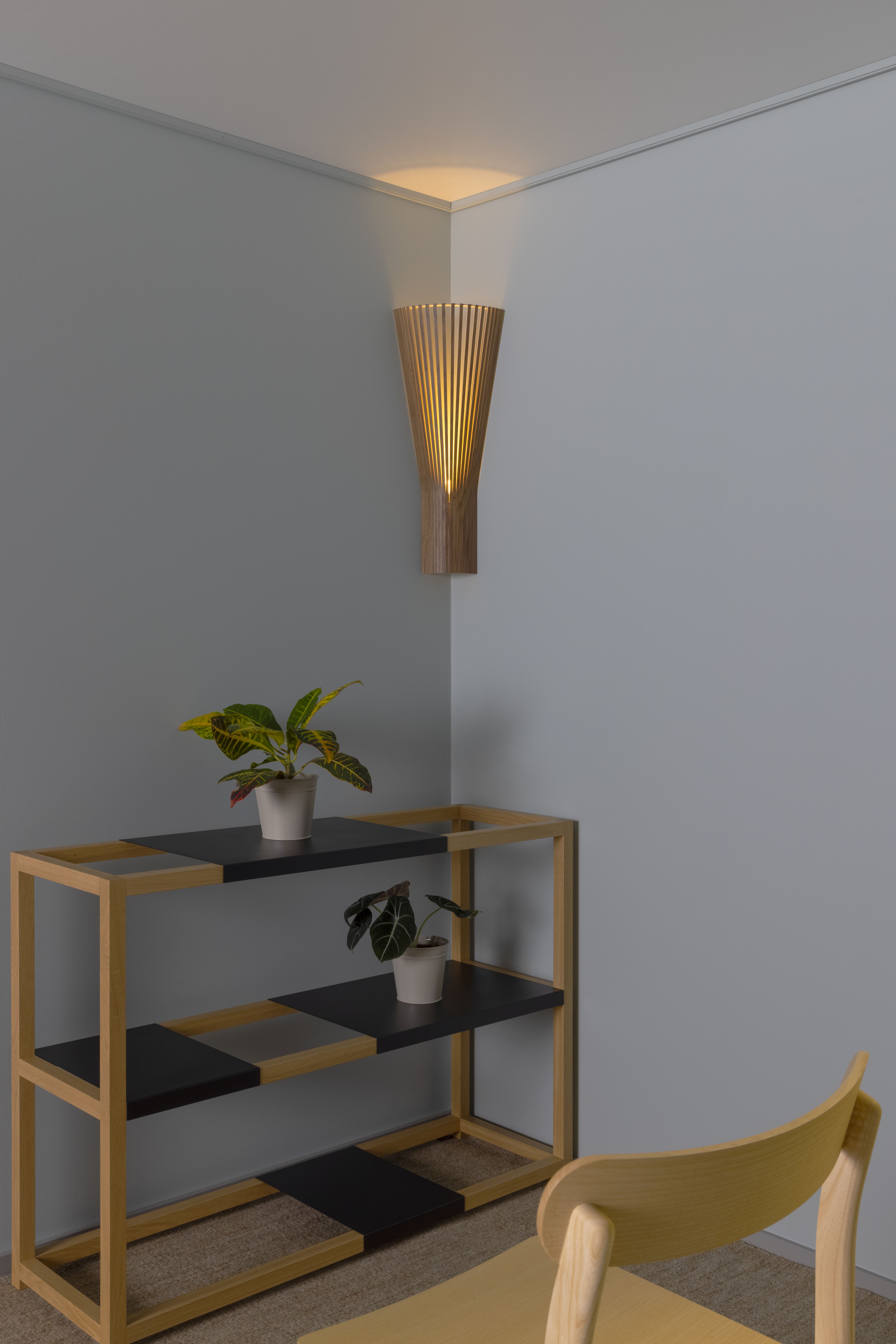 Secto 4236 Eckleuchte: Moderne Wandlampe aus Holz, die warmes Licht in einer Ecke erzeugt.