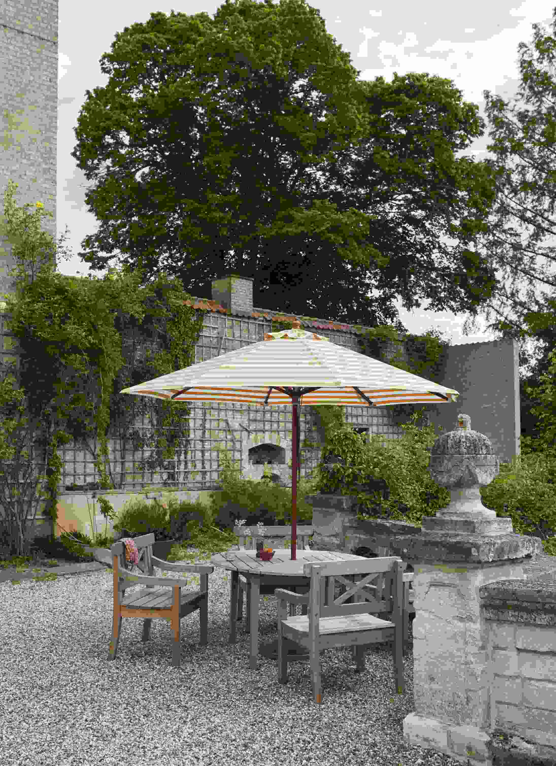Drachmann Tisch von Skagerak by Fritz Hansen: Runder Gartentisch aus Holz mit Sonnenschirm.