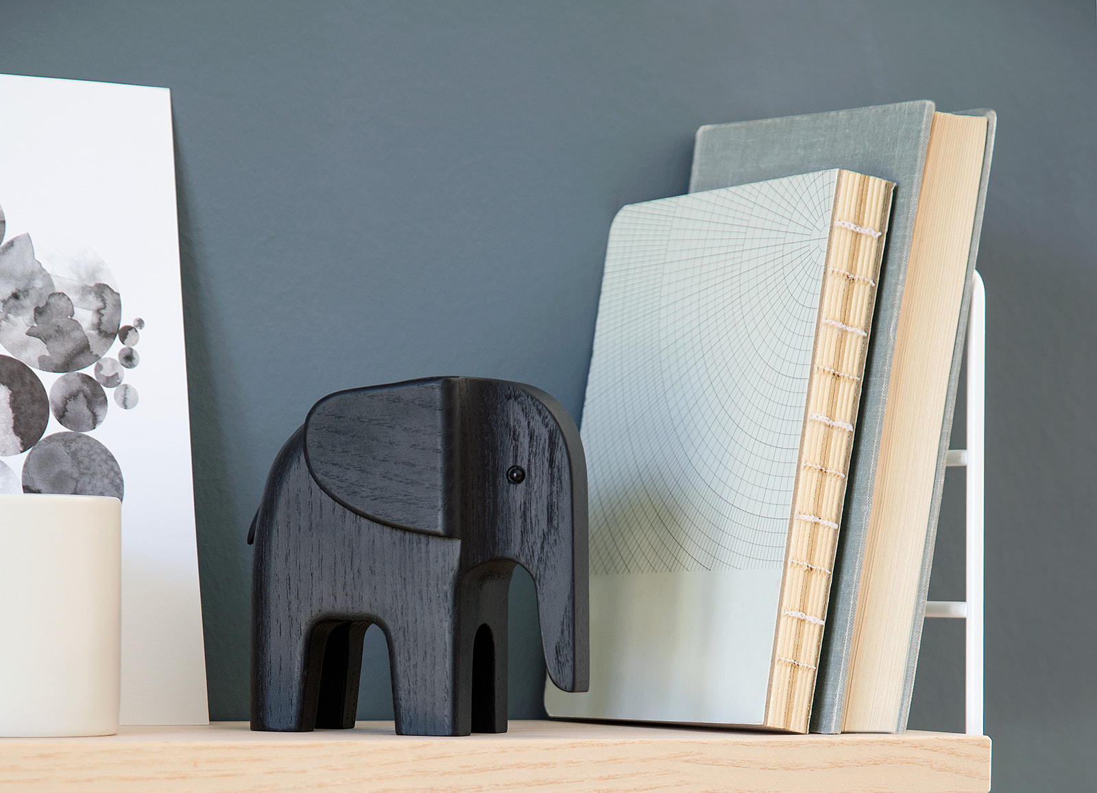 Baby Elefant schwarz von Novoform aus Holz als Dekoration auf einem Regal.