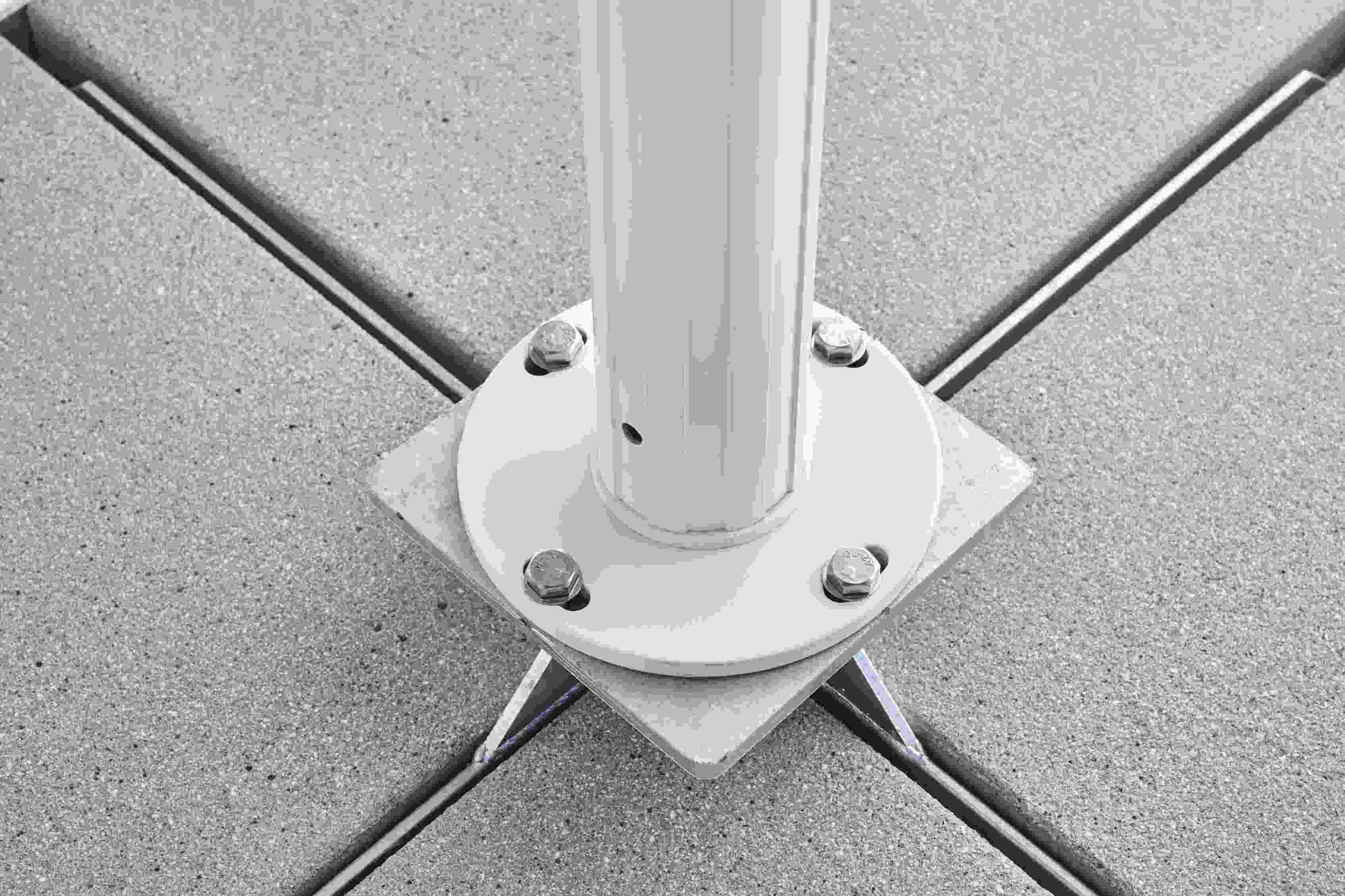 Detailaufnahme des Weishäupl Sonnenschirm-Fußes aus Metall, befestigt auf grauen Terrassenplatten mit Fugen.