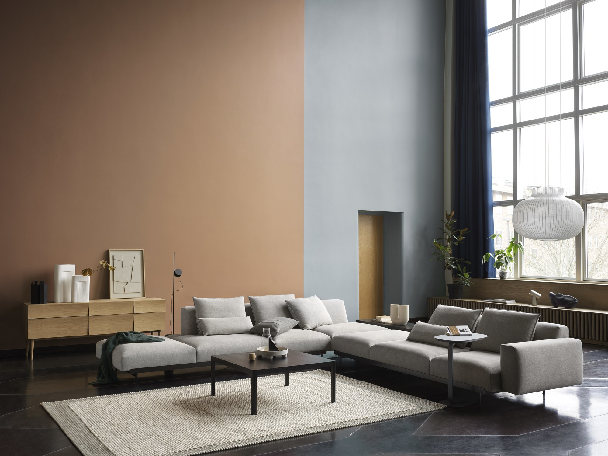 Helles Wohnzimmer mit großem Muuto Reflect Sideboard aus Eiche, grauer Couch und modernem Teppich.
