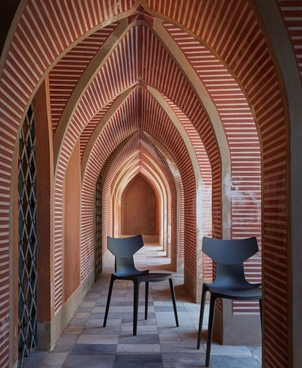 Zwei graue Design Stühle in einem Gang mit roter Backsteinoptik. Moderne Sitzmöbel für stilvolles Wohnen.