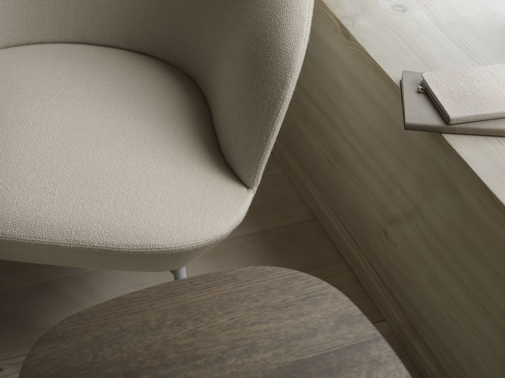 Detailaufnahme vom Muuto Oslo Lounge Chair Sessel in Beige mit kleinem Holztisch und Notizbüchern.