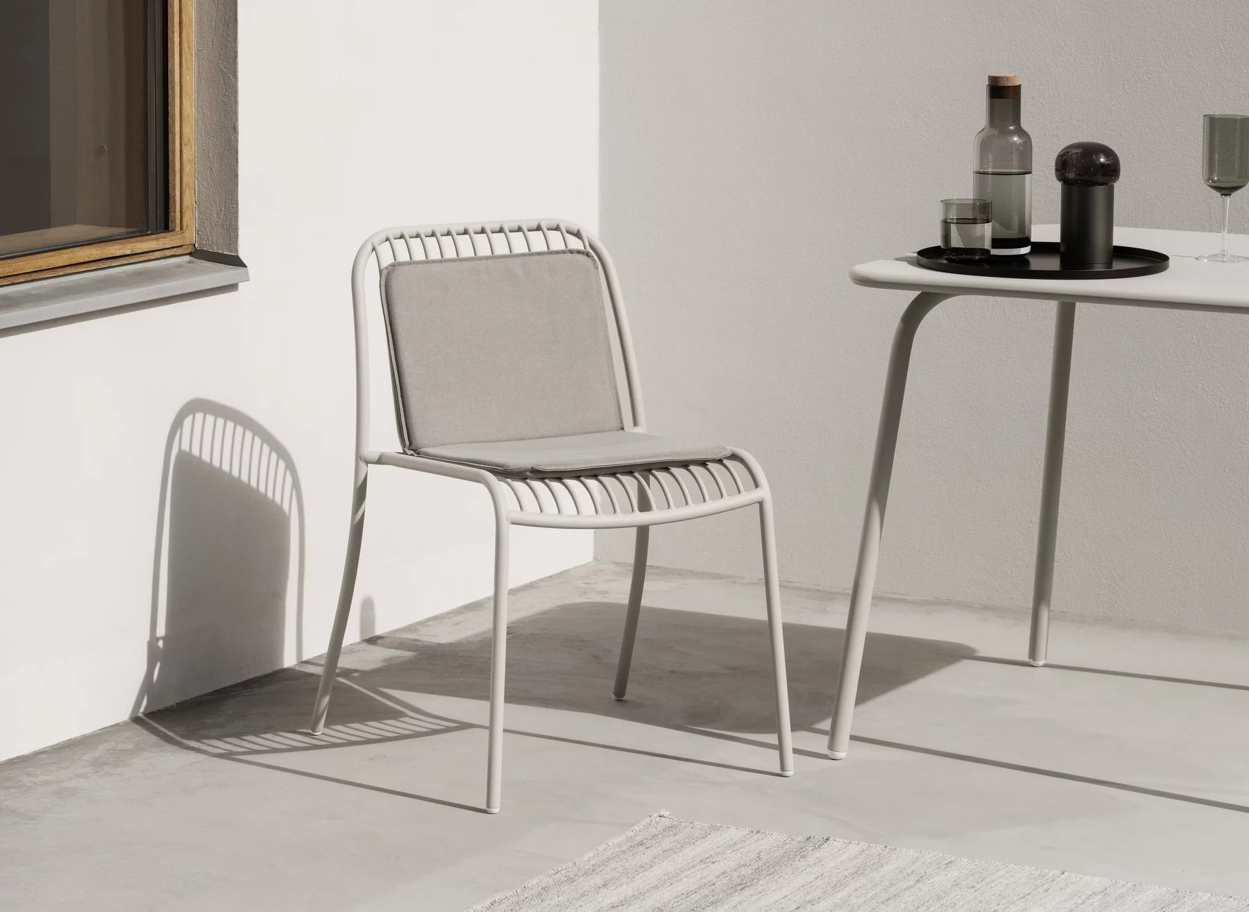 Blomus Kiva Rug Teppich Outdoor: Detailansicht eines grauen Outdoor-Stuhls mit Kissen und Tisch.
