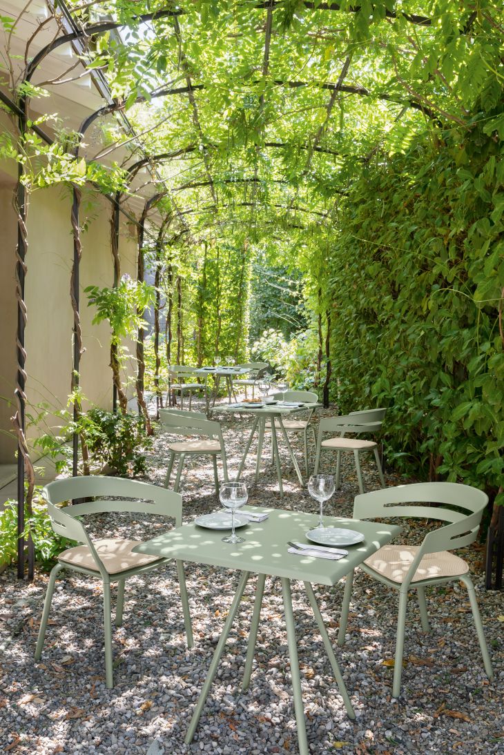 Grüne Gartenmöbel-Sets unter einer Pergola mit Weinreben, ideal für Restaurants und Cafés im Freien.