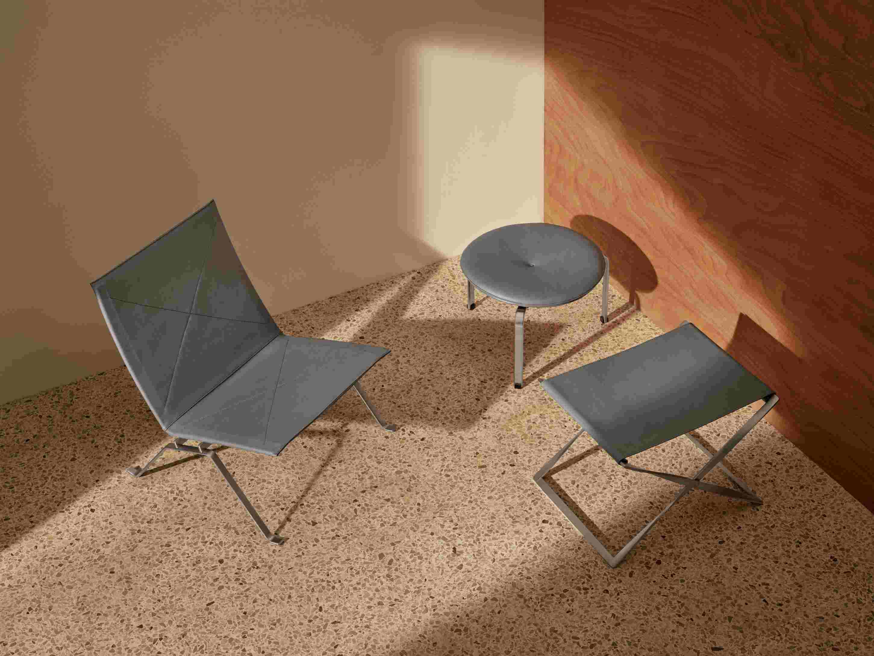 PK91 Falthocker von Fritz Hansen, graues Leder, Stahlgestell, Hocker und Beistelltisch auf Terrazzoboden.