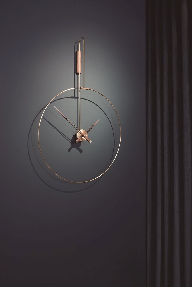 Daro Clock Wanduhr: Moderne Wanduhr mit goldenem Rahmen und Holzdetail vor dunklem Hintergrund.
