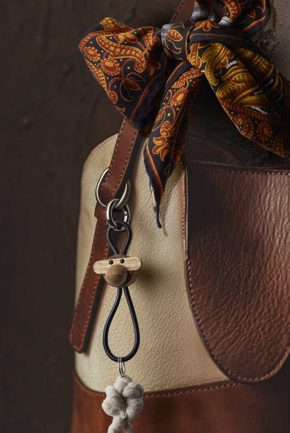 Kay Bojesen Affe Schlüsselanhänger aus Holz und Leder an einer Handtasche mit Tuch.