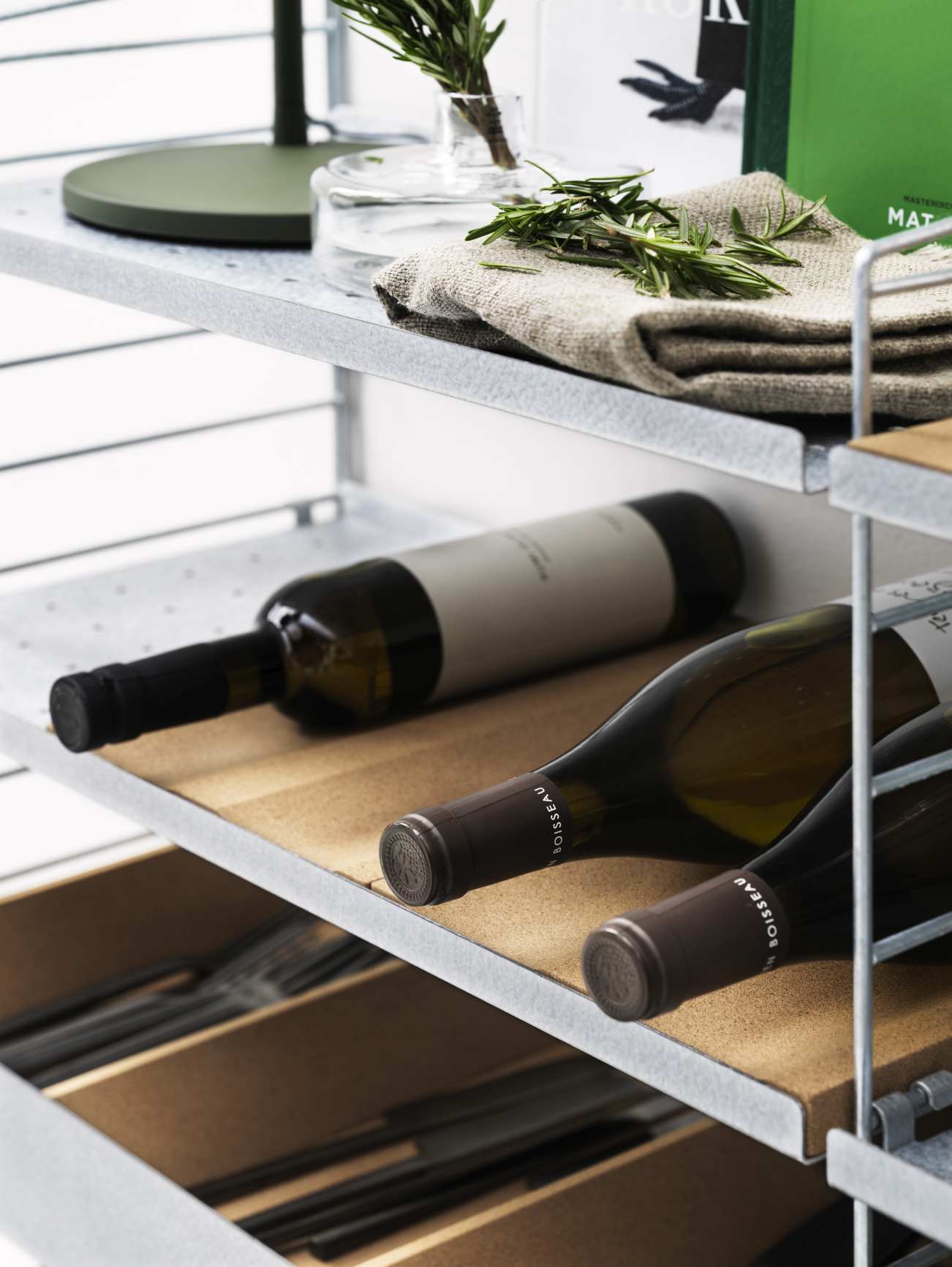 Detailaufnahme eines String Regalsystems mit Wein, Kräutern und Besteck. Flur KONFIGURATIONEN Aufbewahrung.