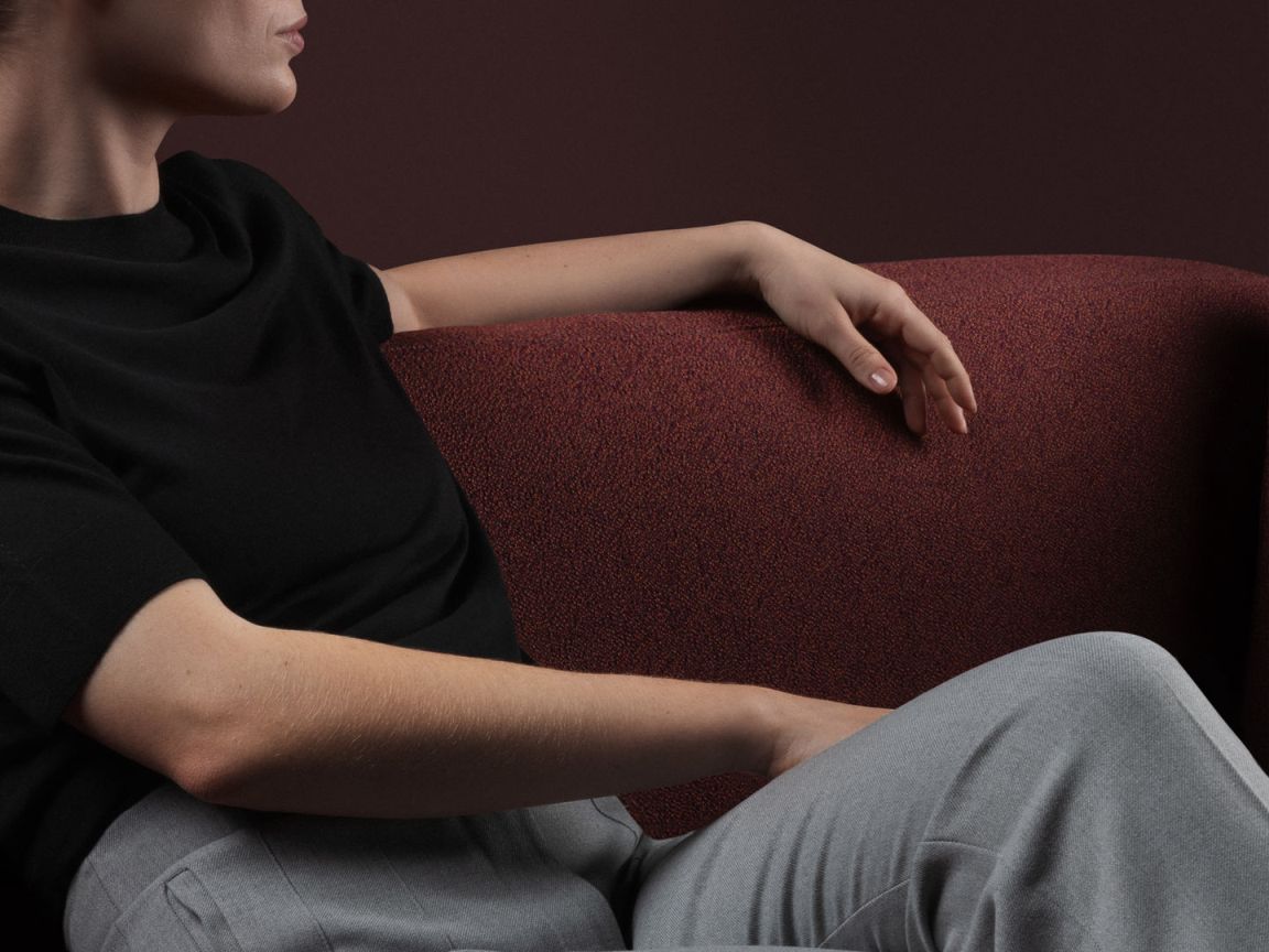 Frau entspannt auf rotem Designersofa. Modernes Wohnzimmer-Interieur mit stilvollem Sofa und bequemer Sitzgelegenheit.