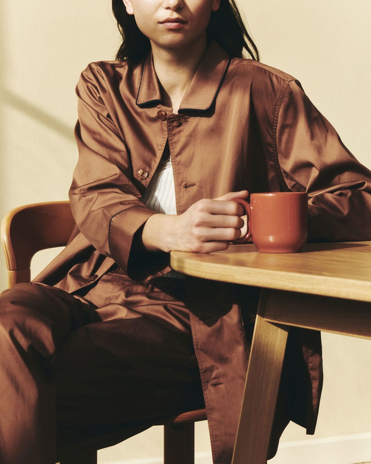 Frau sitzt am Hay Triangle Leg Table Esstisch mit einer Tasse Kaffee in der Hand.