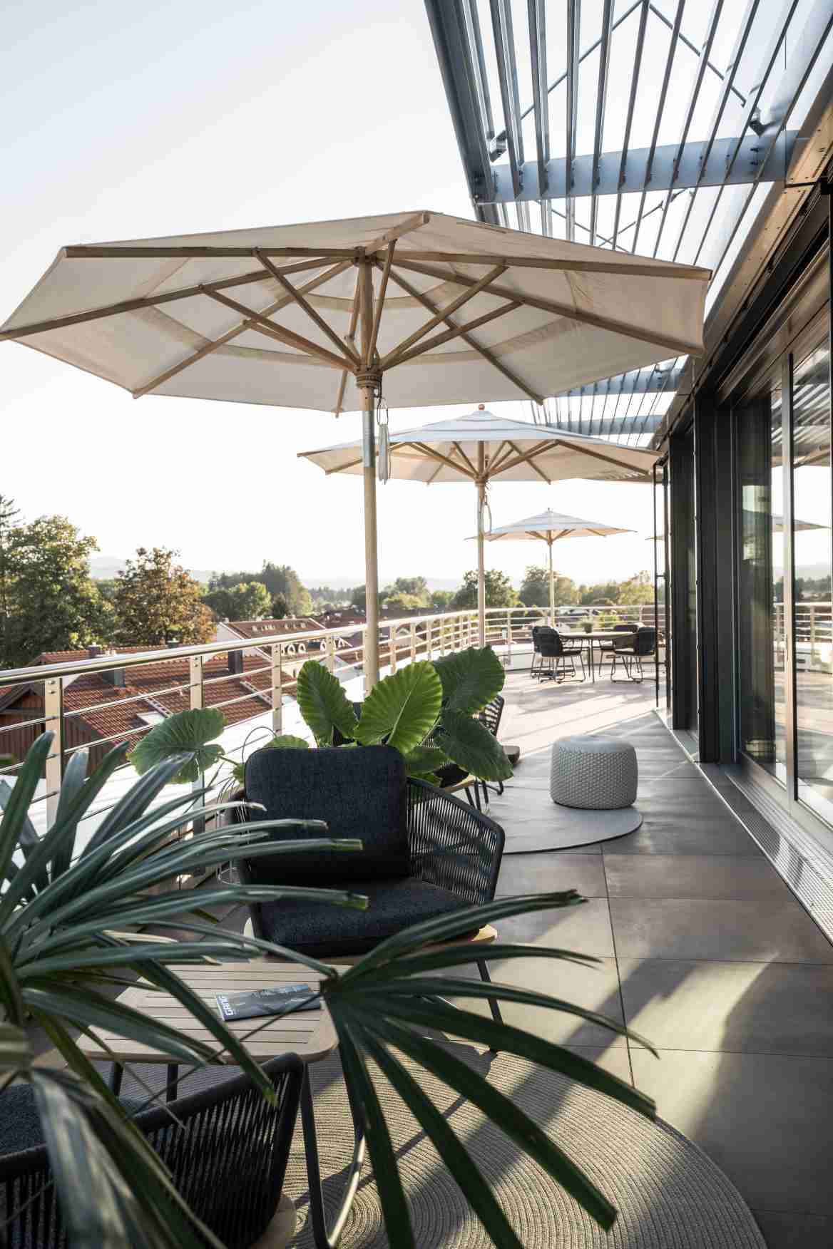 Weishäupl Klassiker Schirm auf einer Dachterrasse mit Loungemöbeln und Blick ins Grüne, Sonnenschutz für den Außenbereich.