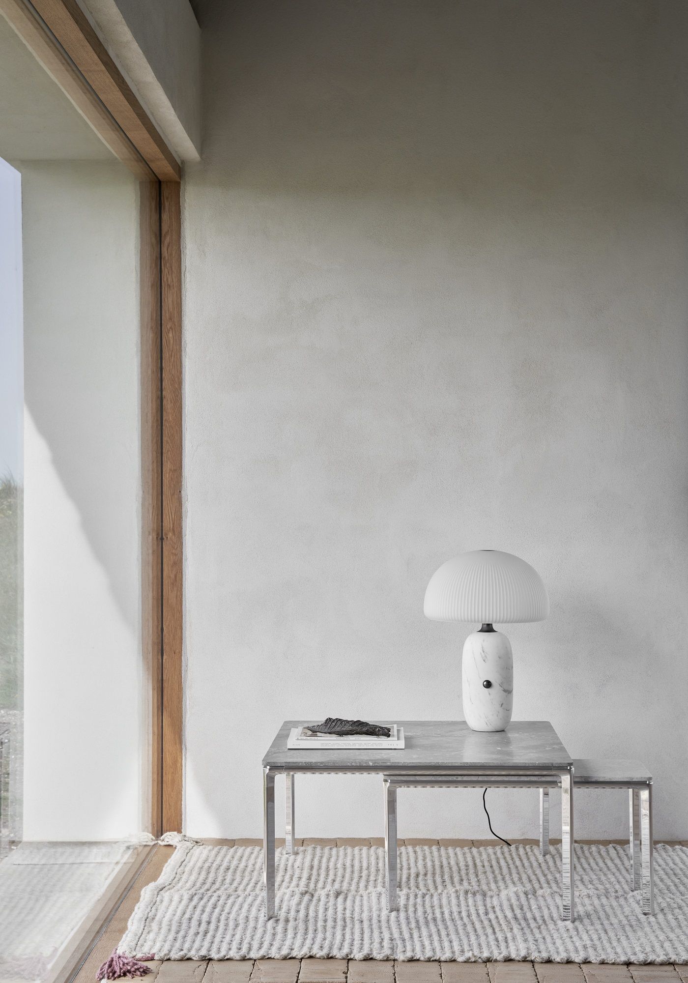 Nahaufnahme des Vipp Couchtisch-Sets mit quadratischer Tischplatte, Lampe und Buch auf einem Teppich.