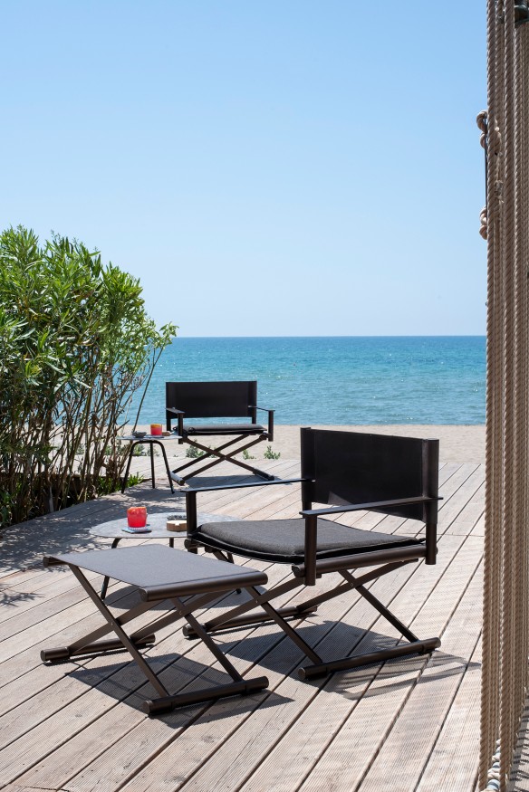 Terra Fußhocker von Emu, Outdoor-Fußstütze aus Metall, passend zu Gartenmöbeln, auf Holzterrasse am Meer.