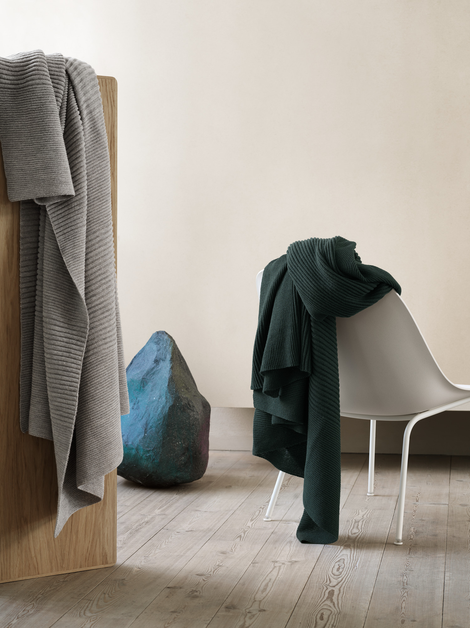 Muuto Fiber Lounge Chair mit Kufengestell, weiß, mit dunkelgrüner Strickdecke, minimalistisches Design.