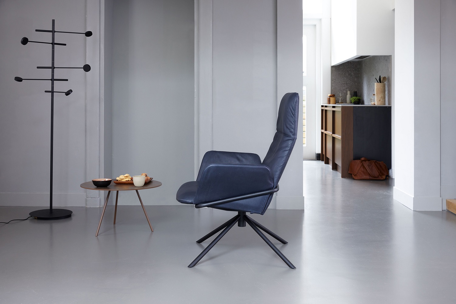 Kingpin Floor Stehleuchte Japth: Moderne Stehlampe in Schwarz neben Sessel und Beistelltisch im Wohnraum.