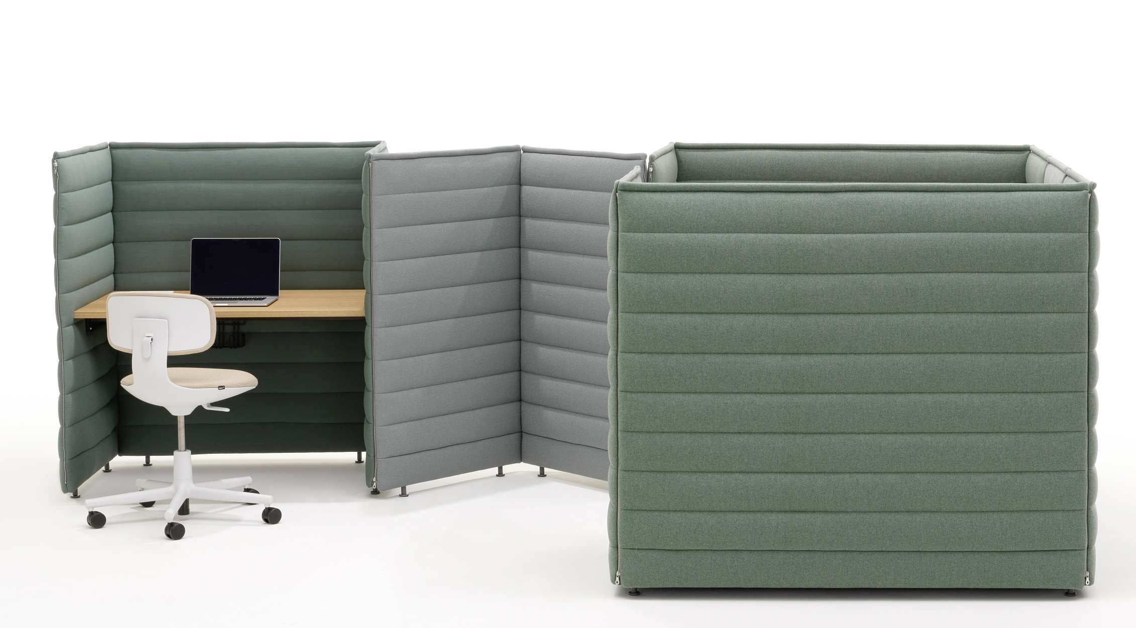 Vitra Alcove Plus Desk Small Schreibtisch mit grünen Akustikwänden, Holztischplatte, Bürostuhl und Laptop.