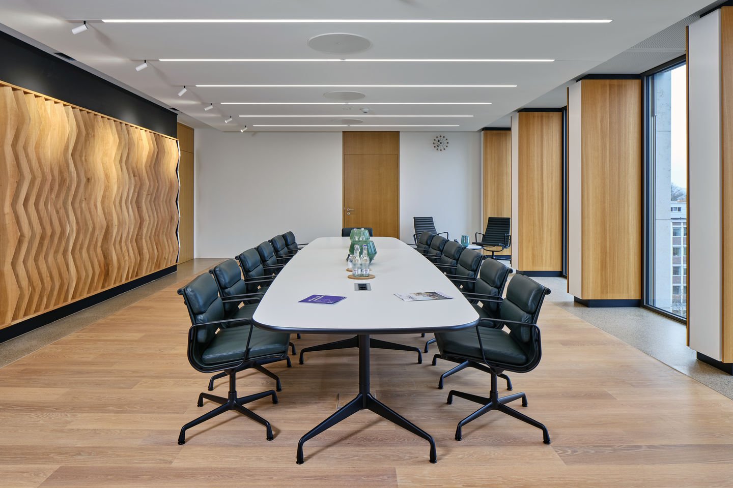 Konferenzraum mit langem Tisch und vielen Vitra Soft Pad EA 207 Sesseln mit schwarzem Gestell.