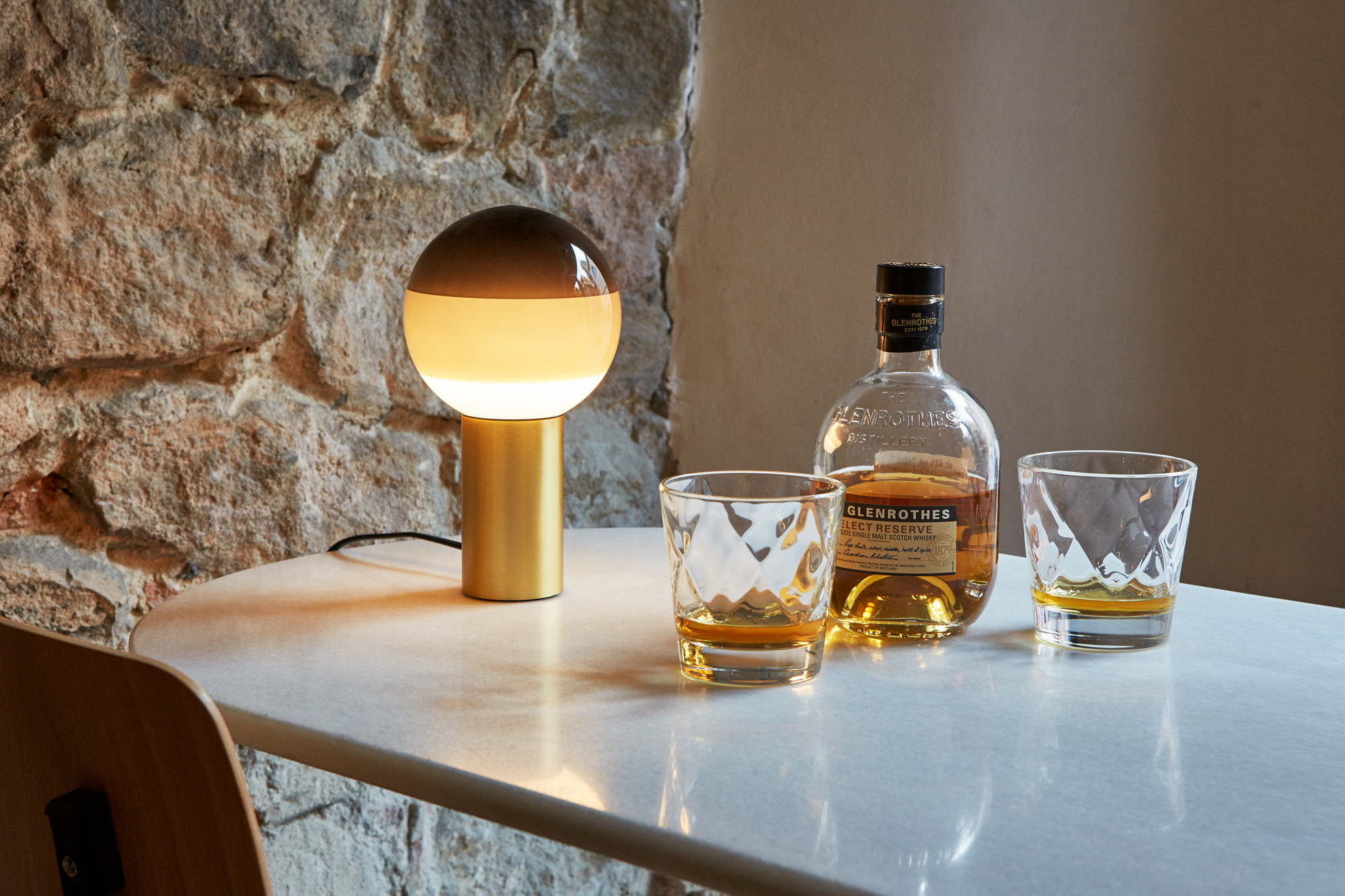 Dipping Light M LED Tischleuchte von Marset in Bernstein und Messing auf Tisch.