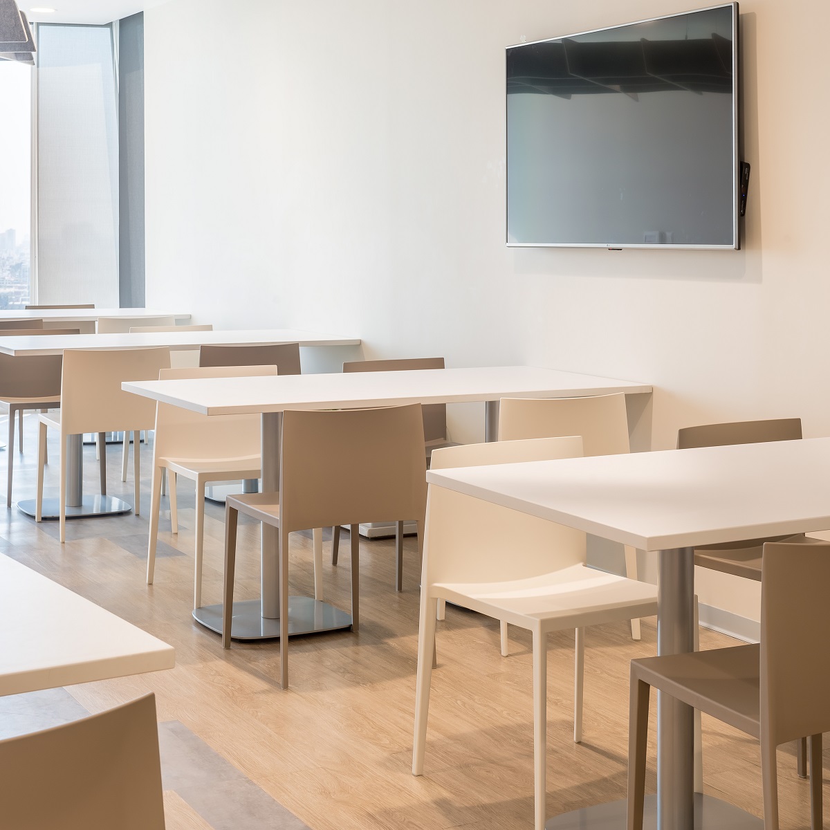 Innenaufnahme eines Konferenzraums mit weißen Tischen und Sail Stühlen von Andreu World, stapelbare Designstühle in Beige.