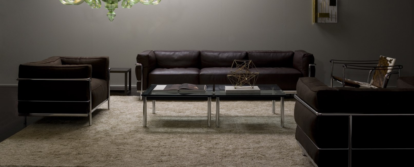 Braunes Cassina Sofa Dreisitzer und Sessel mit Stahlrahmen in einem Wohnzimmer mit Teppich.