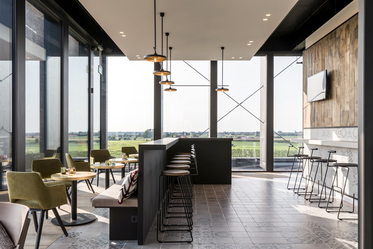 Innenaufnahme eines modernen Restaurants mit Tiki Barhockern von Extremis und Blick ins Grüne.