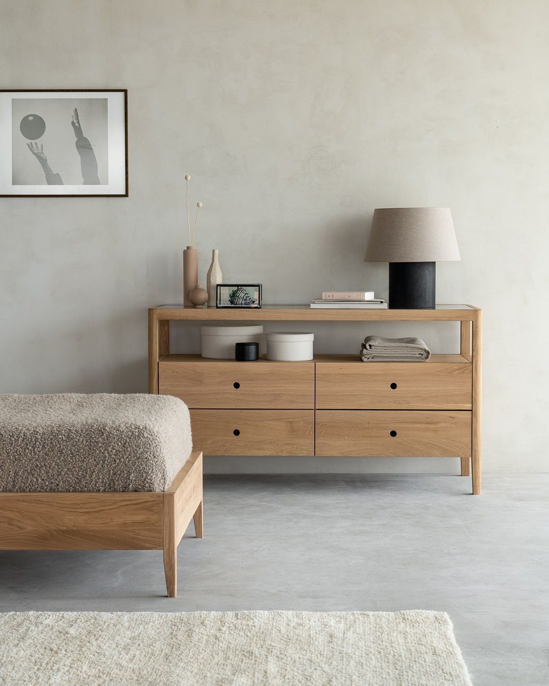 Ethnicraft Spindle Kommode aus Eiche mit vier Schubladen im Schlafzimmer mit Bett und Dekoration.