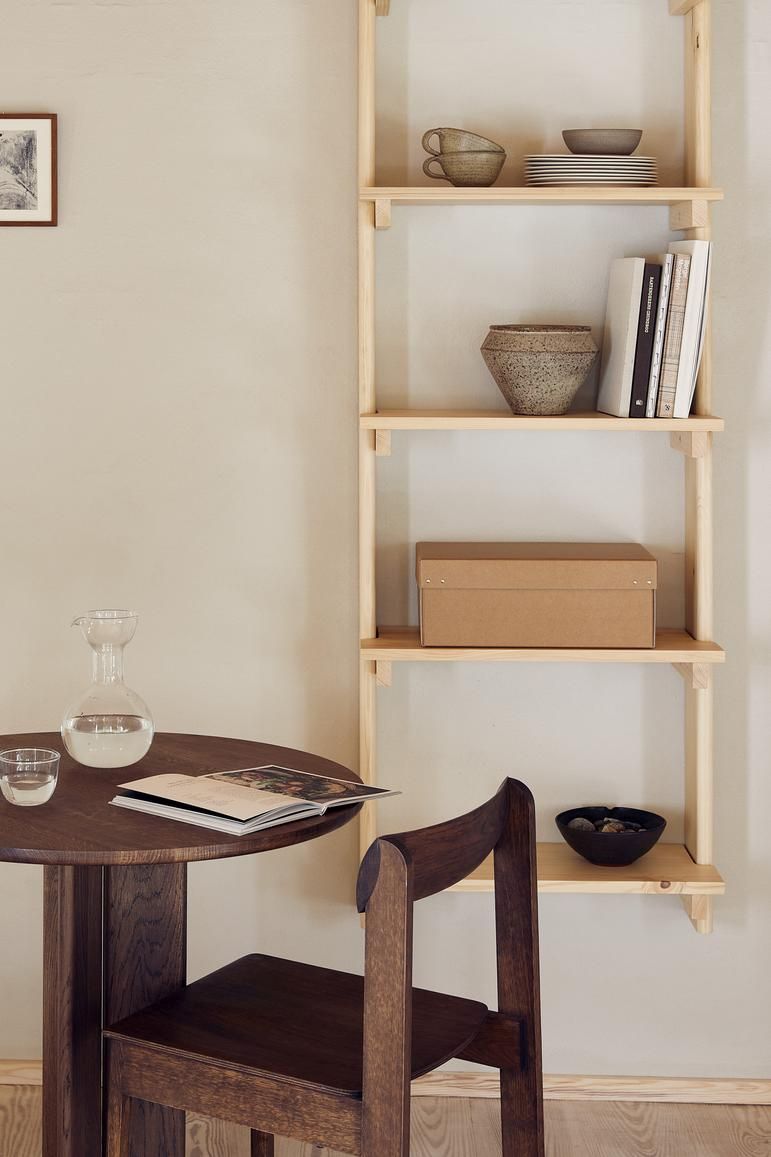 Beam Wandregal von Form & Refine aus hellem Holz mit fünf Fächern, dekoriert mit Geschirr und Büchern.