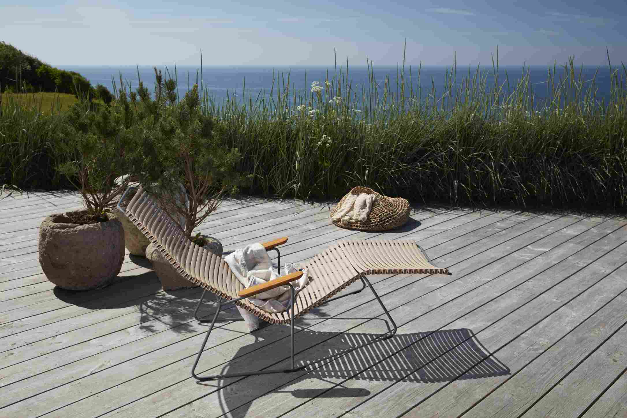 Click Sunlounger Sonnenliege von Houe auf Holzterrasse mit Meerblick, ideal für entspannte Stunden im Freien.