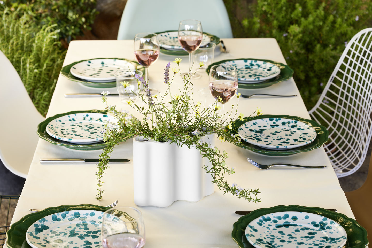 Esstisch mit Gedeck und Vitra DKR Wire Chair Stuhl im Hintergrund, ideal für Gartenmöbel und stilvolles Outdoor-Dining.